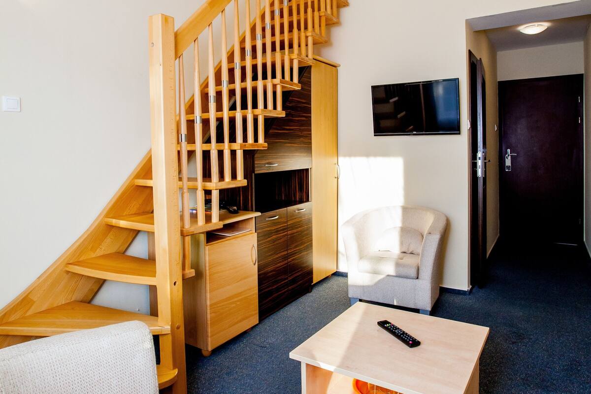 A modern living room with a wooden staircase, a flat-screen TV, and a comfortable seating area.