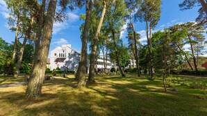 Een hotel met een groot gebouw, omringd door een verzorgd gazon en hoge bomen.