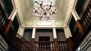 Una gran escalera con candelabro, columnas ornamentadas y un techo decorativo.