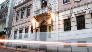 Un edificio histórico con una entrada destacada, un cartel que dice 'sant Jordi hostels' y un rastro de luz moderno que indica movimiento.