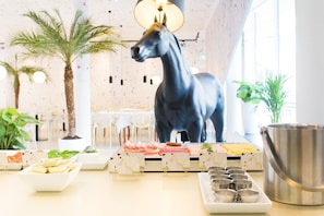 Un comedor con una estatua decorativa de un caballo, un bufé con diversas opciones de comida y una olla de metal grande.