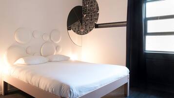 A modern bedroom with a white bed, circular wall decorations, and a unique wall-mounted guitar-shaped light fixture.
