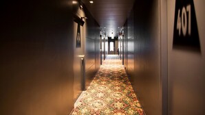 A hallway with a patterned carpet, dark walls, and a sign indicating room number 407. - MABI City Centre (Maastricht)