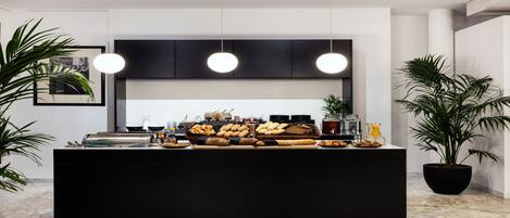A modern kitchen with a black countertop, three pendant lights, and various food items.