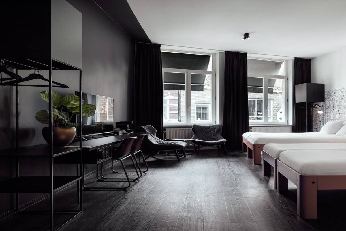 A modern hotel room with two beds, a desk, and a chair.