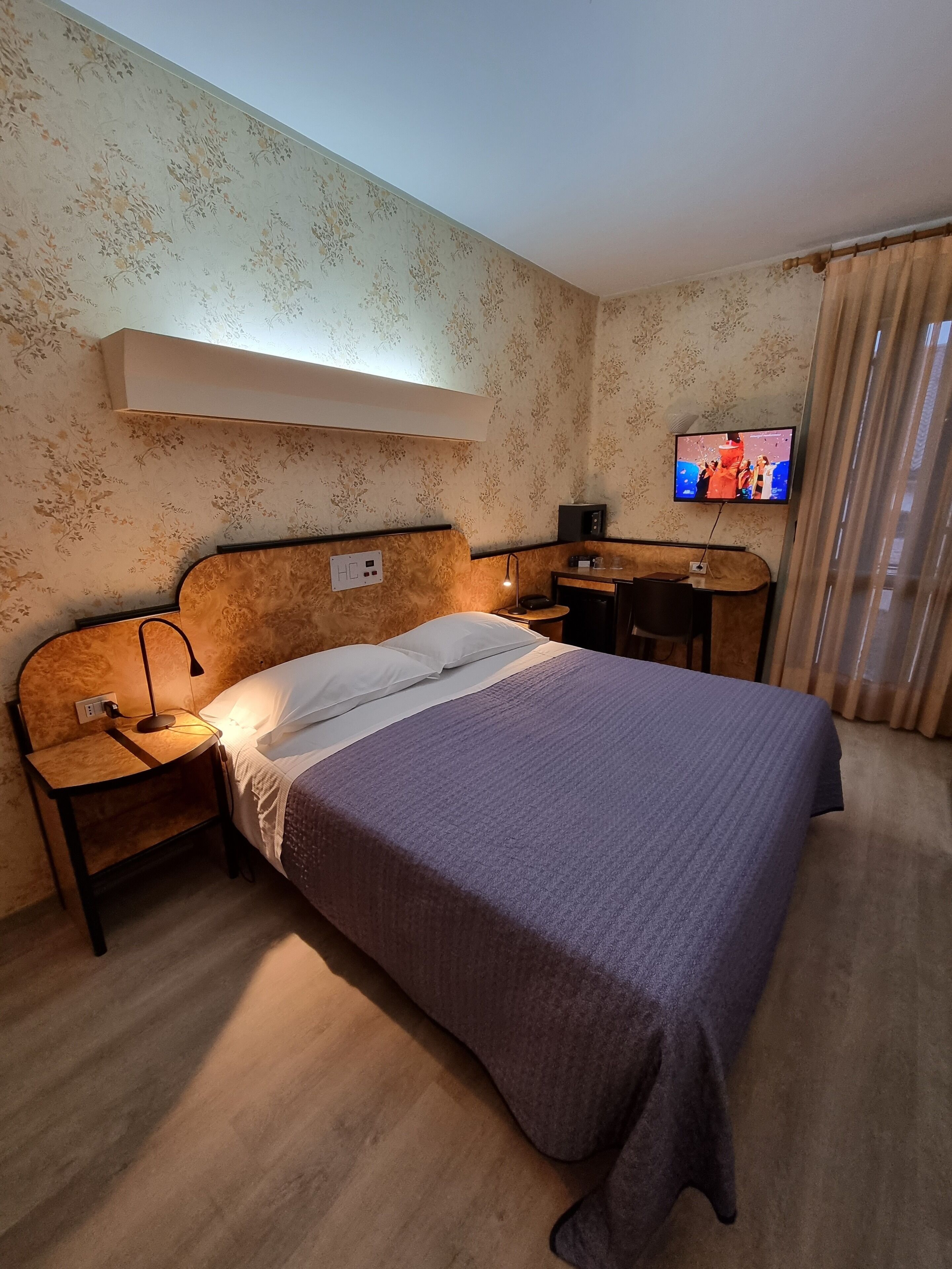 Een hotelkamer met een bed, nachtkastjes, een televisie en een bureau.