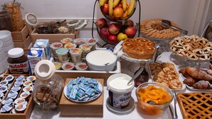 A buffet table with various food items including fruits, pastries, and condiments.