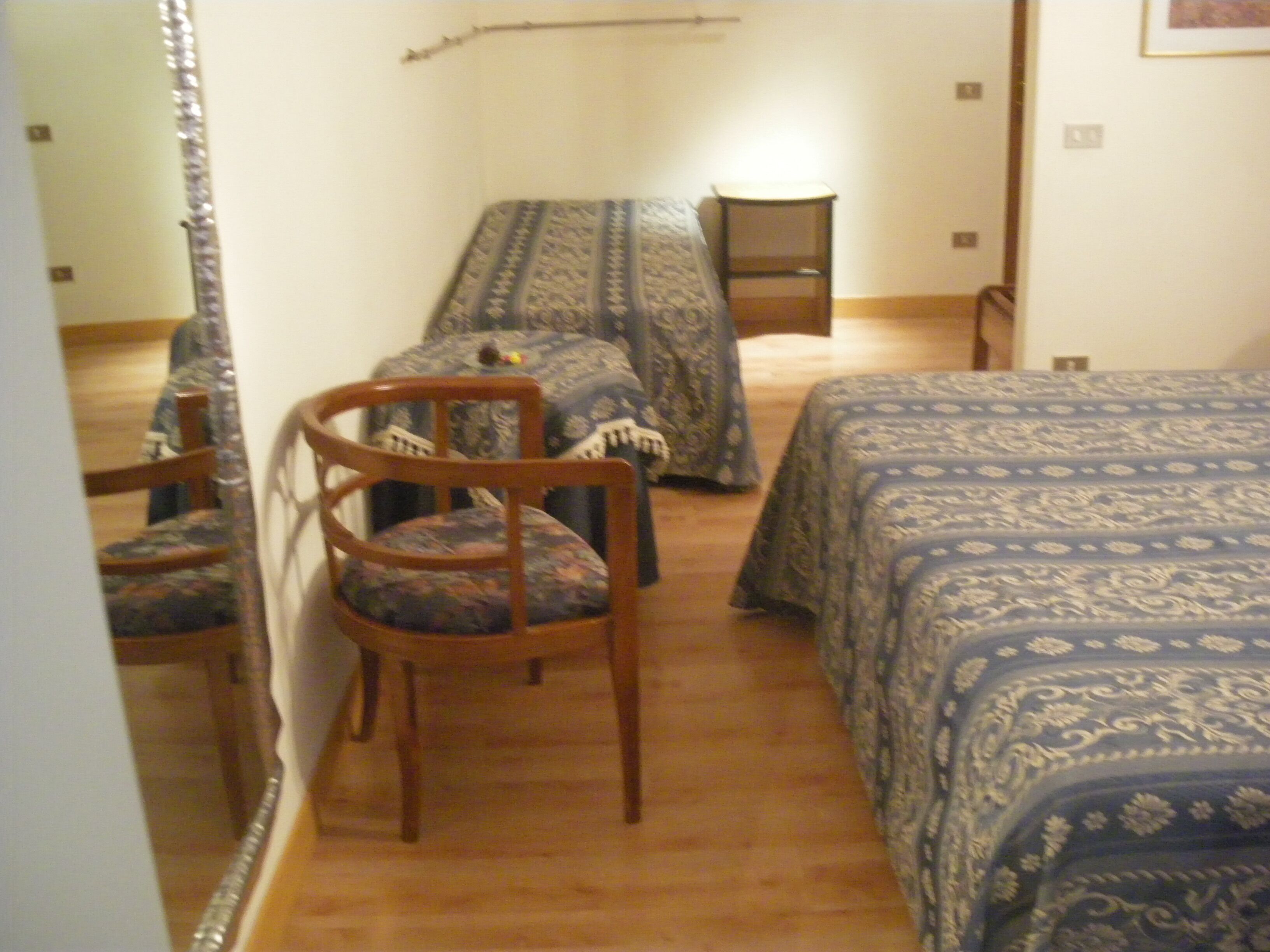 A bedroom with a bed, a chair, and a mirror.