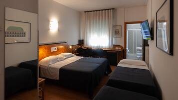 A hotel room with two beds, a desk, a chair, a TV, and a window with curtains.