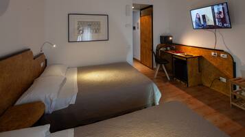 Habitación de hotel con dos camas, un escritorio, un televisor y un cuadro en la pared.
