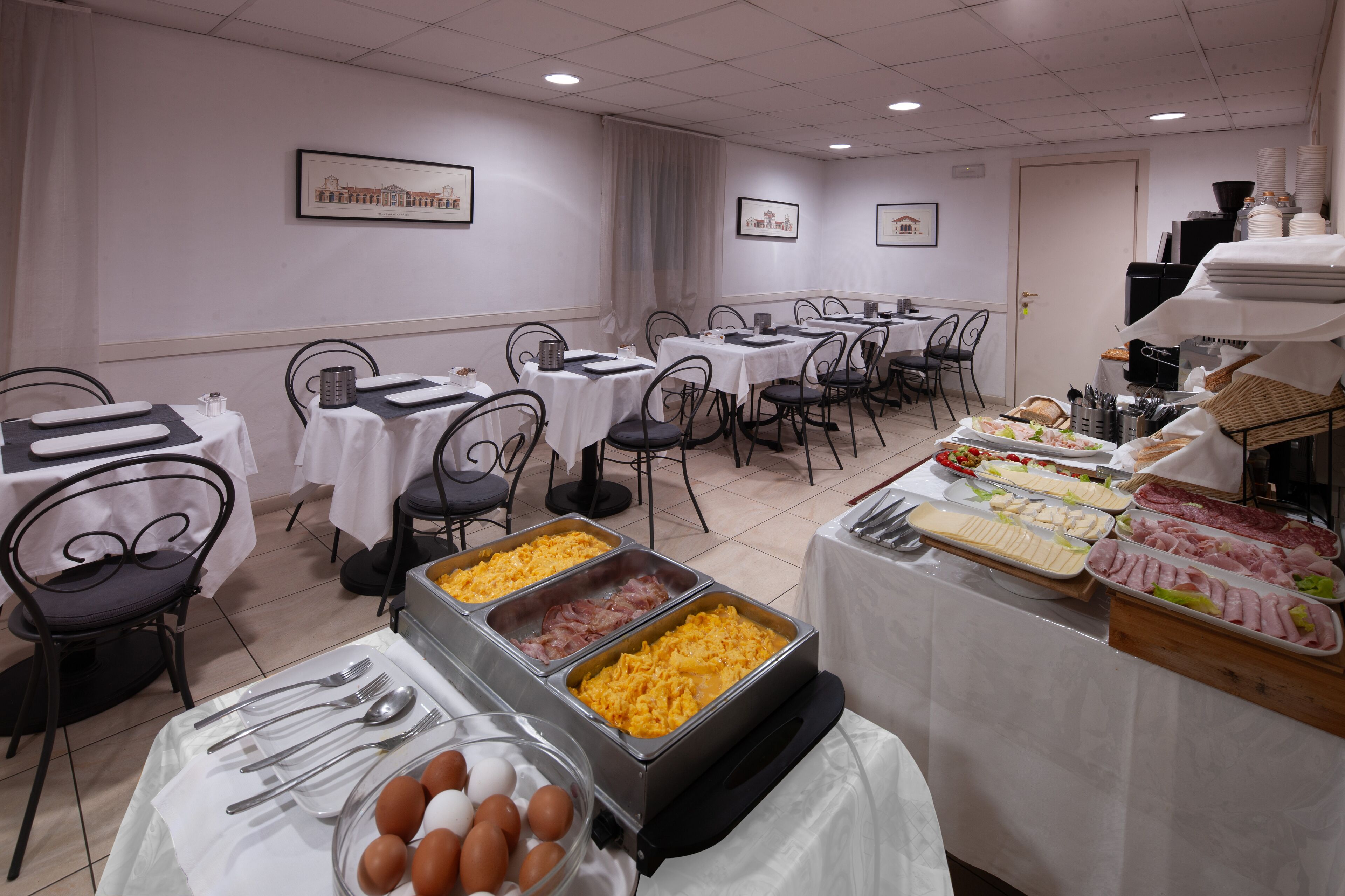 Ein reichhaltiges Buffet mit verschiedenen Speisen und Besteck, auf Tischen mit Stühlen drapiert.