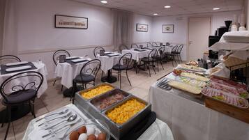 Ein reichhaltiges Buffet mit verschiedenen Speisen und Besteck, auf Tischen mit Stühlen drapiert.