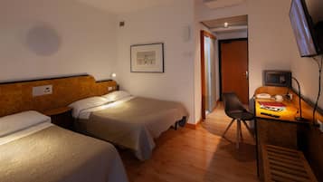 Ein Hotelzimmer mit zwei Betten, einem Schreibtisch mit Stuhl, einem Fernseher und einem gerahmten Bild an der Wand.