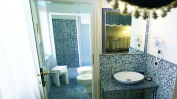 Une salle de bain avec un sol carrelé aux motifs bleus et blancs, un lavabo blanc et des toilettes.
