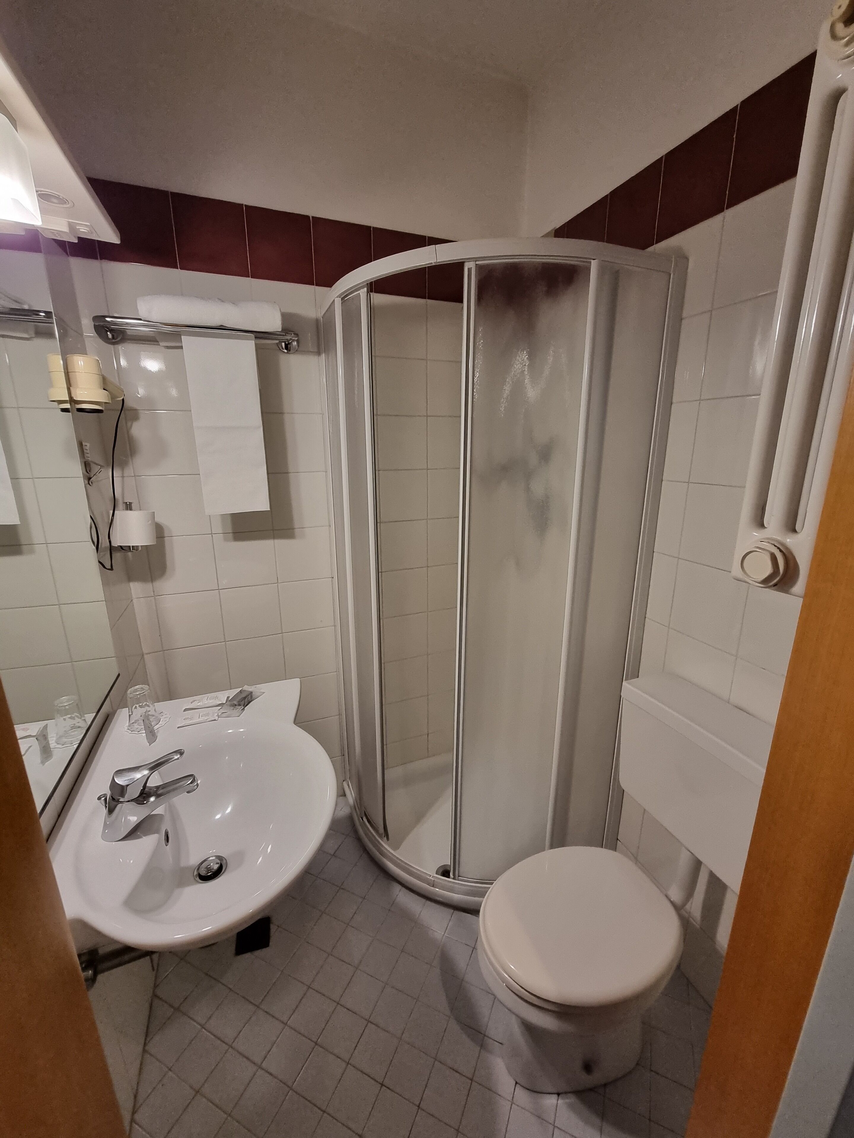 A bathroom with a white sink, toilet, and a glass-enclosed shower stall.