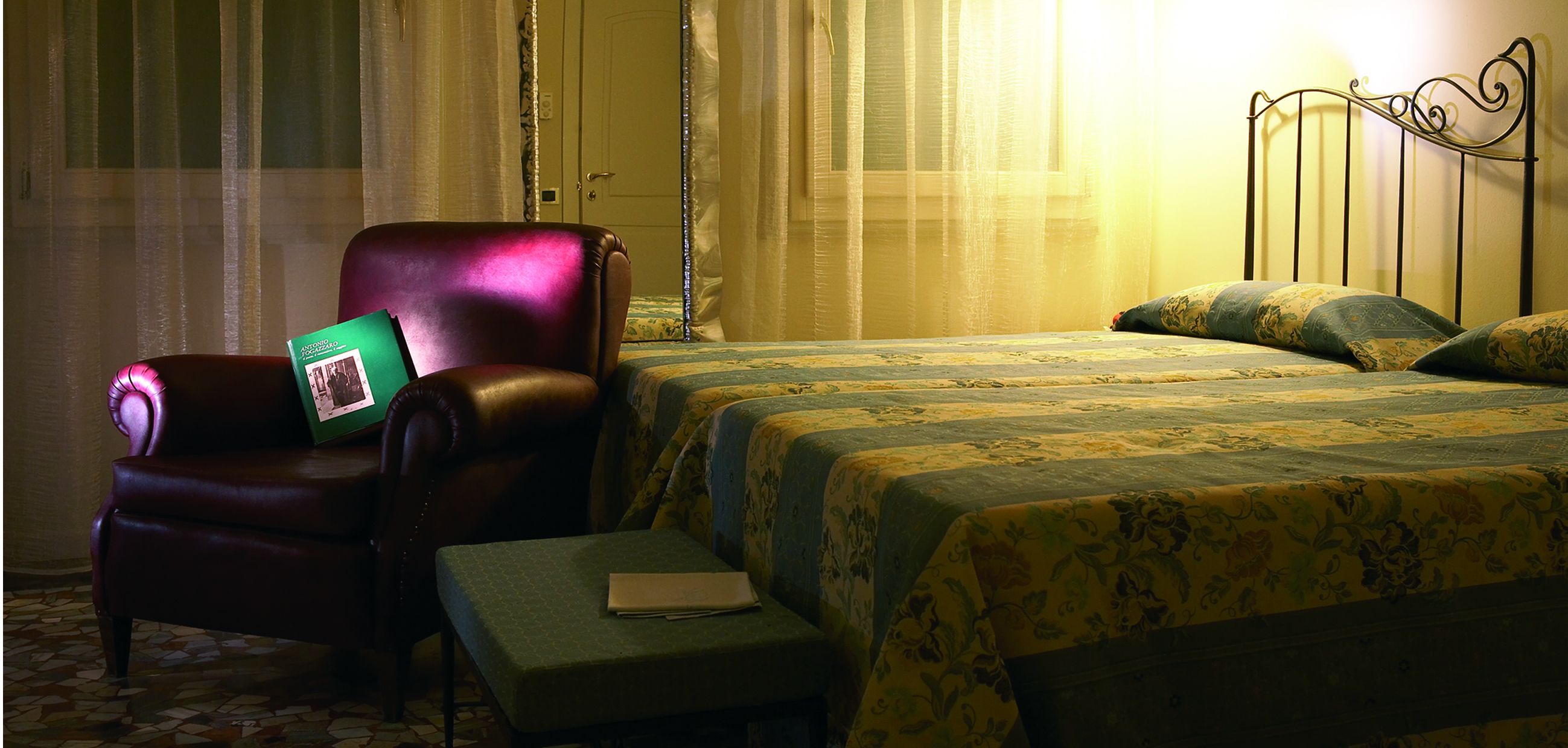 Una camera d'albergo con un letto, una sedia, un tavolino e una porta.