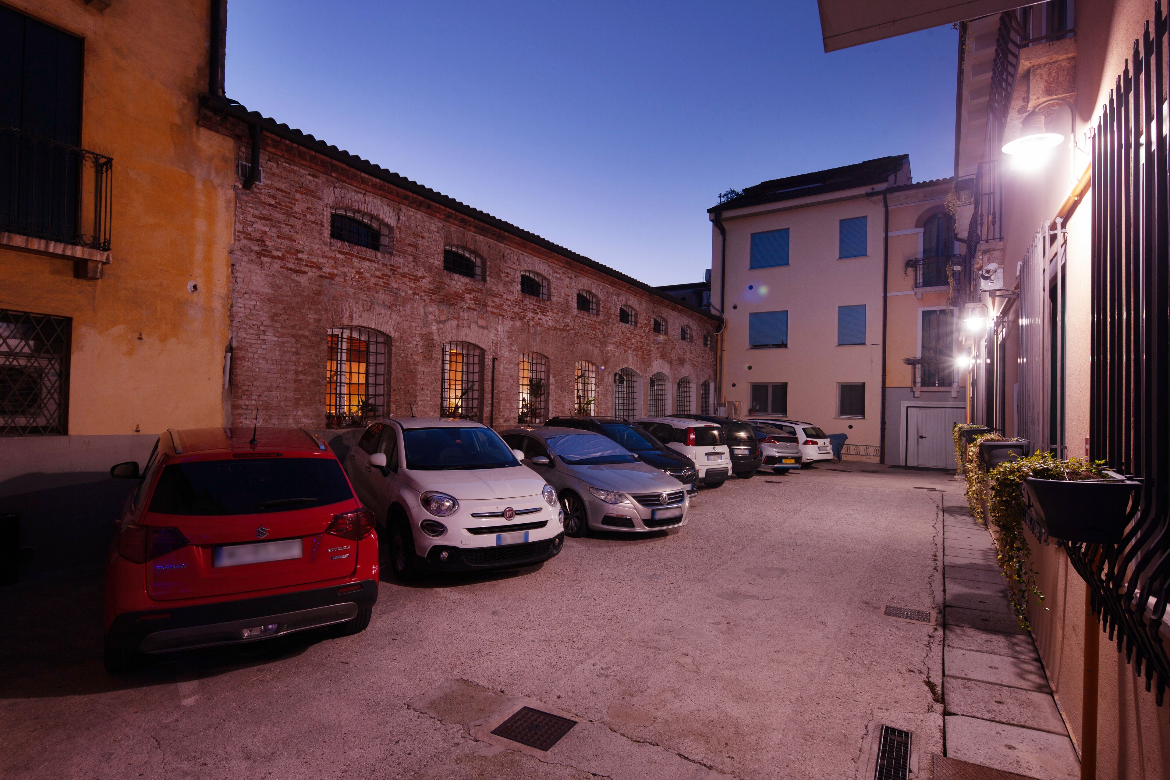 A row of parked cars in a narrow street with buildings on either side.