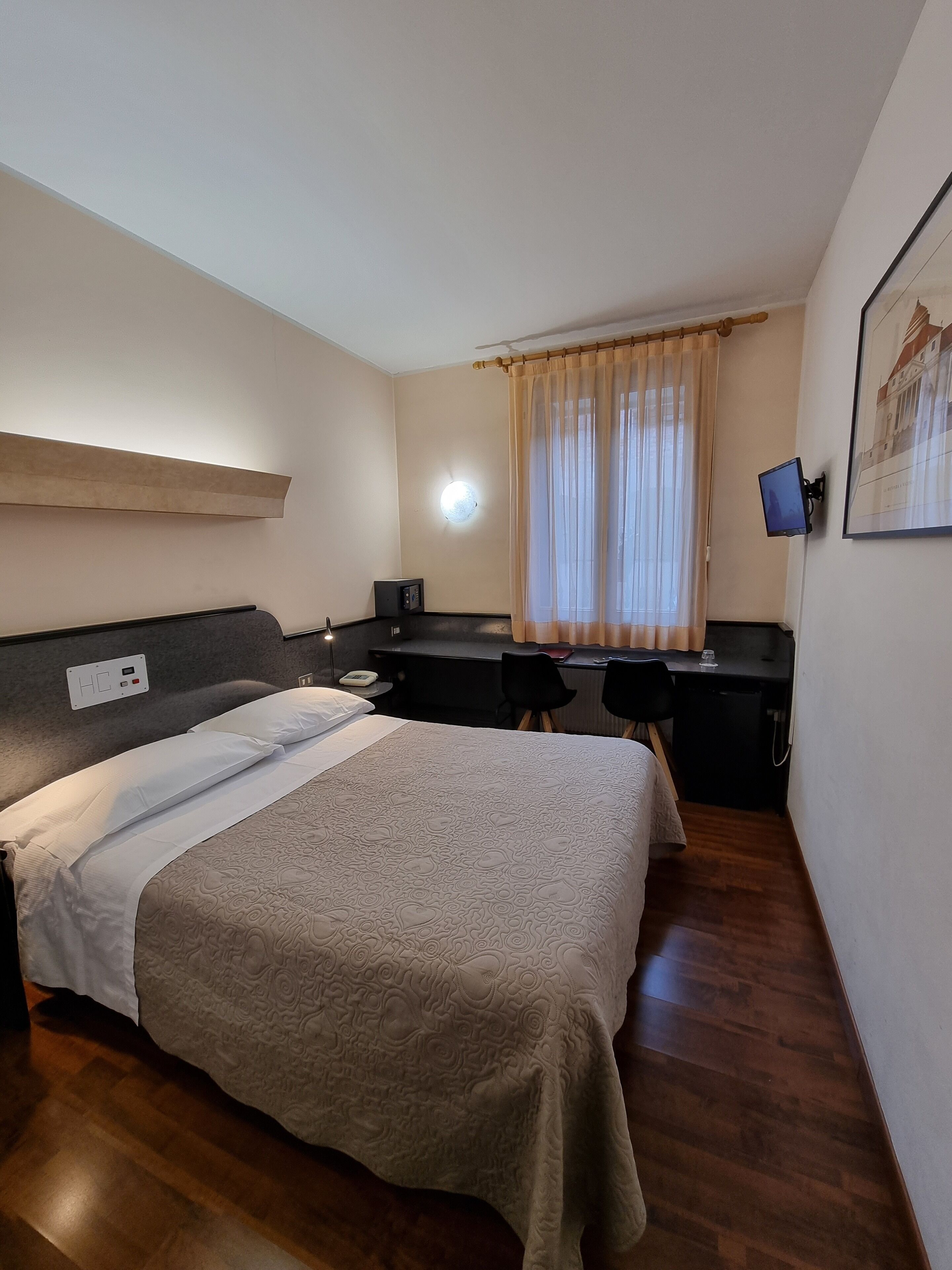 Een hotelkamer met een bed, bureau en stoel.