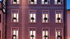 A hotel with multiple balconies, a ground floor reception, and a sign indicating a parking area.