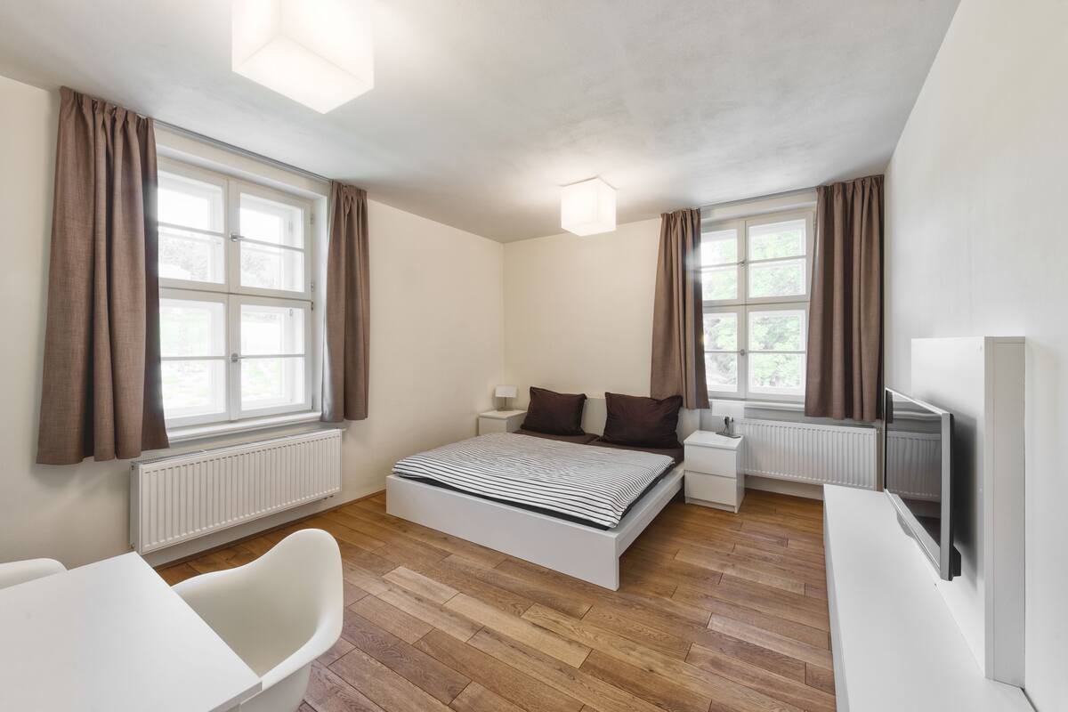 Une chambre à coucher moderne avec un lit, des tables de chevet, une chaise et un téléviseur.