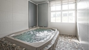 A bathroom with a freestanding bathtub, a window, and tiled flooring. - Theresian Apartment (Ostruzna)