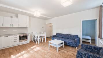 A modern living room with a sofa, a coffee table, and a dining area with chairs and a table.