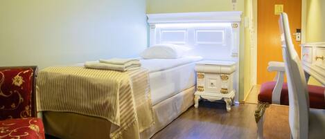 A hotel room with a bed, bedside table, and a chair.
