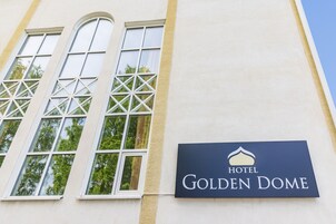 Letrero de hotel que dice 'HOTEL GOLDEN DOME', con un diseño arquitectónico moderno que incluye amplias ventanas y una fachada limpia.