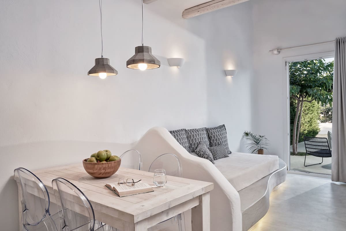 Una habitación moderna y minimalista con un sofá blanco, una mesa de comedor de madera y lámparas colgantes.