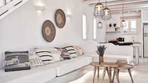 A modern living room with a white sofa, decorative wall art, and a wooden coffee table. - Naxian Utopia Luxury Villas & Suites (Naxos)