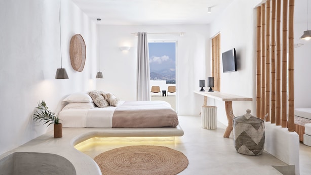 A modern bedroom with a bed, bedside table, and a view of the outdoors. - Naxian Utopia Luxury Villas & Suites (Naxos)