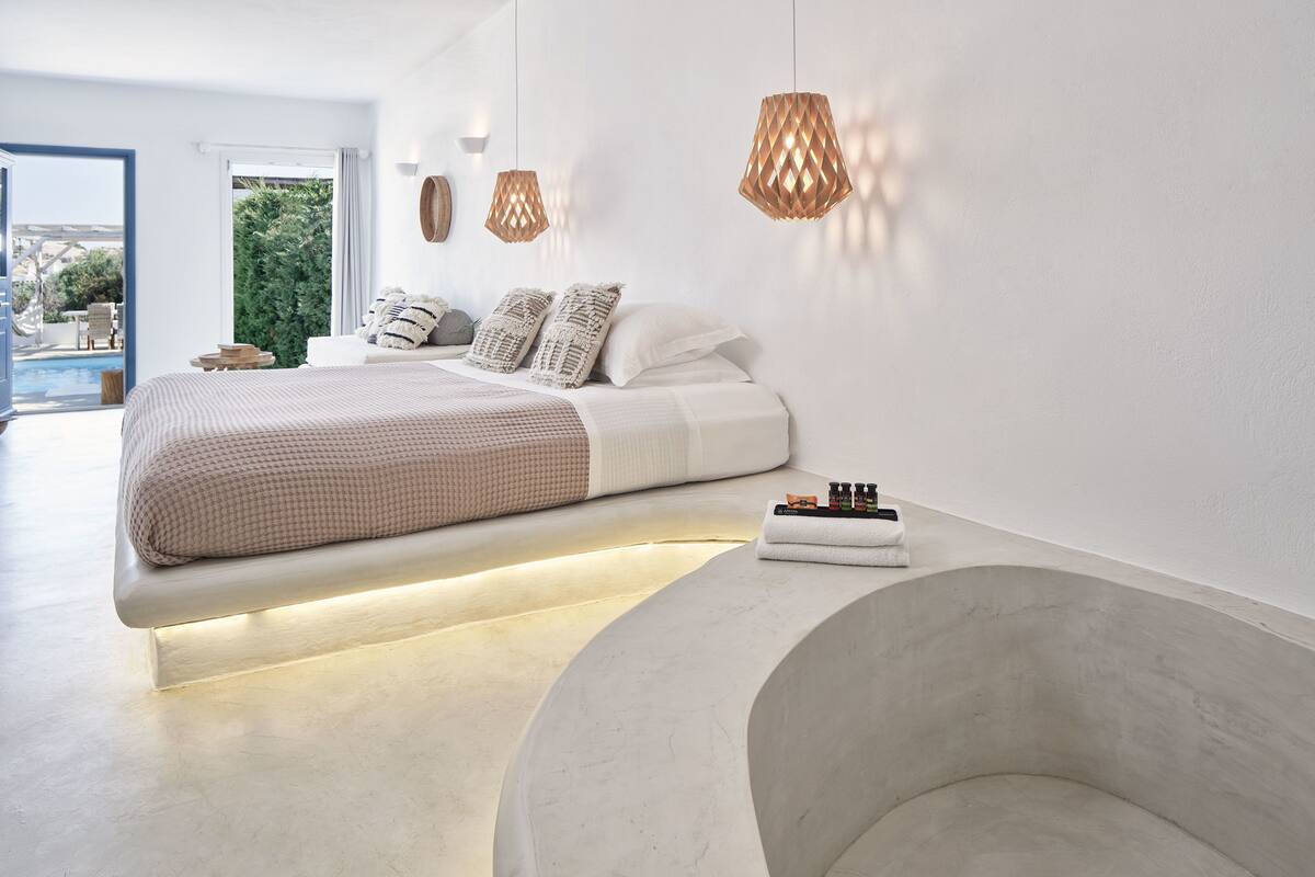 Un dormitorio moderno con cama, mesita de noche y un banco curvo.