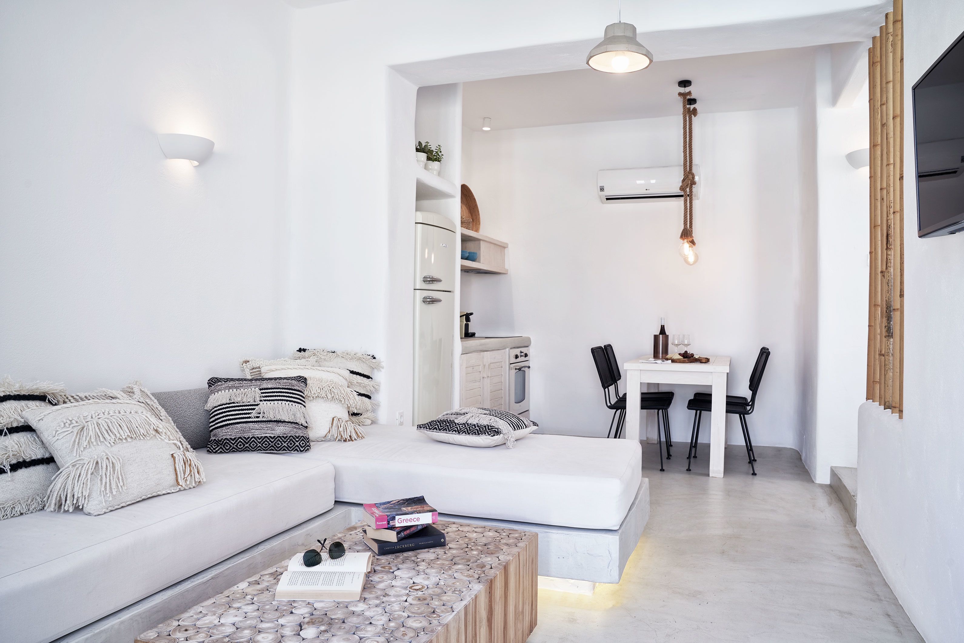 Una sala moderna con un sofá, una mesa de centro con libros y un comedor con una mesa y sillas.