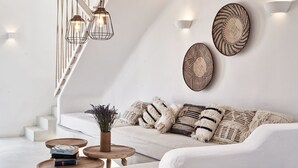 A modern living room with a white sofa, wooden coffee table, and hanging light fixtures. - Naxian Utopia Luxury Villas & Suites (Naxos)