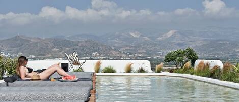 Une femme se détend au bord d’une piscine, avec une vue sur les montagnes.