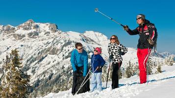 A group of people on a snowy mountain with ski equipment, standing on a snow-covered slope with a clear sky and mountains in the background.