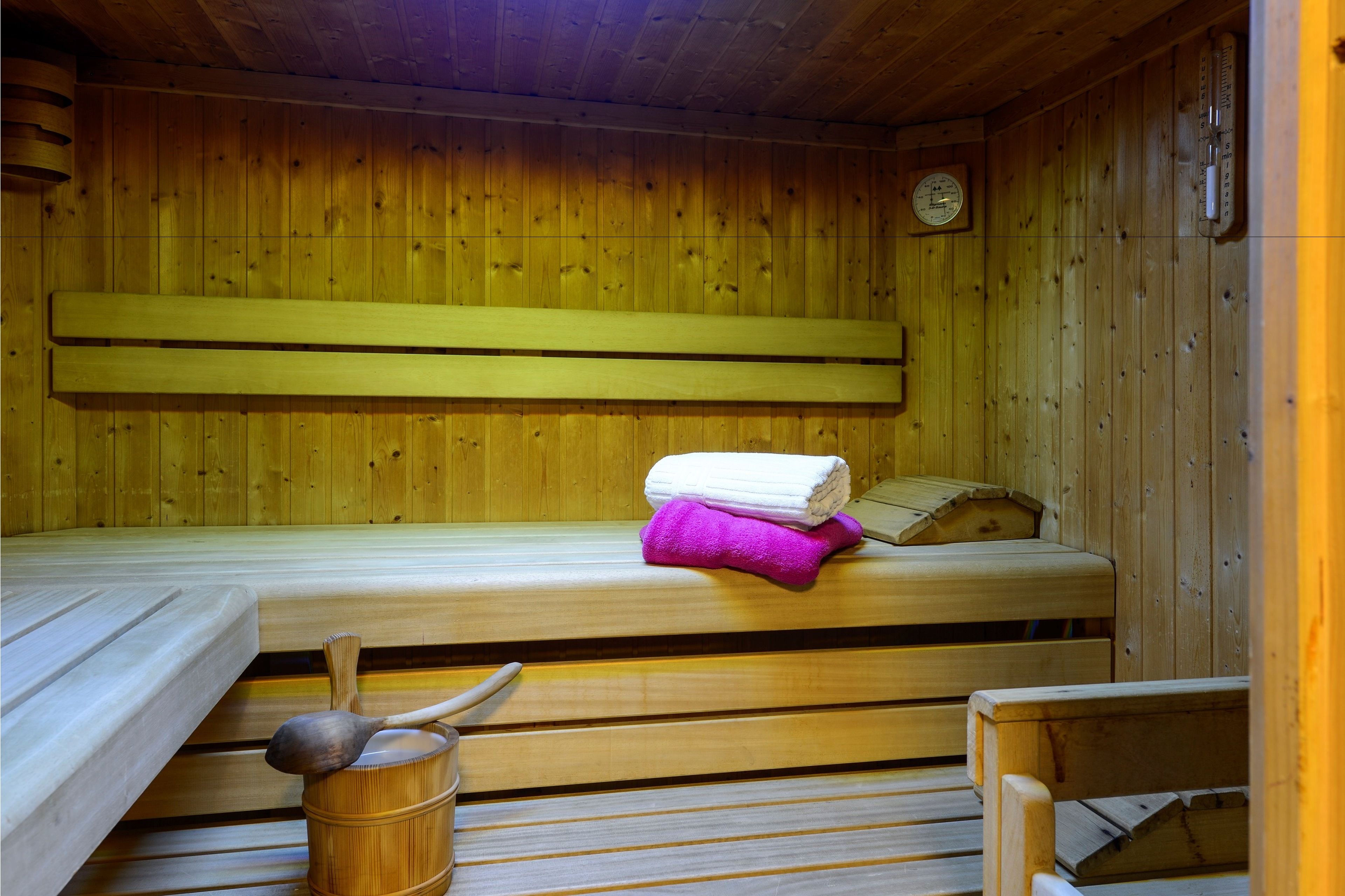 Eine Holzsauna mit Bänken und einer Sitzbank mit Handtüchern.