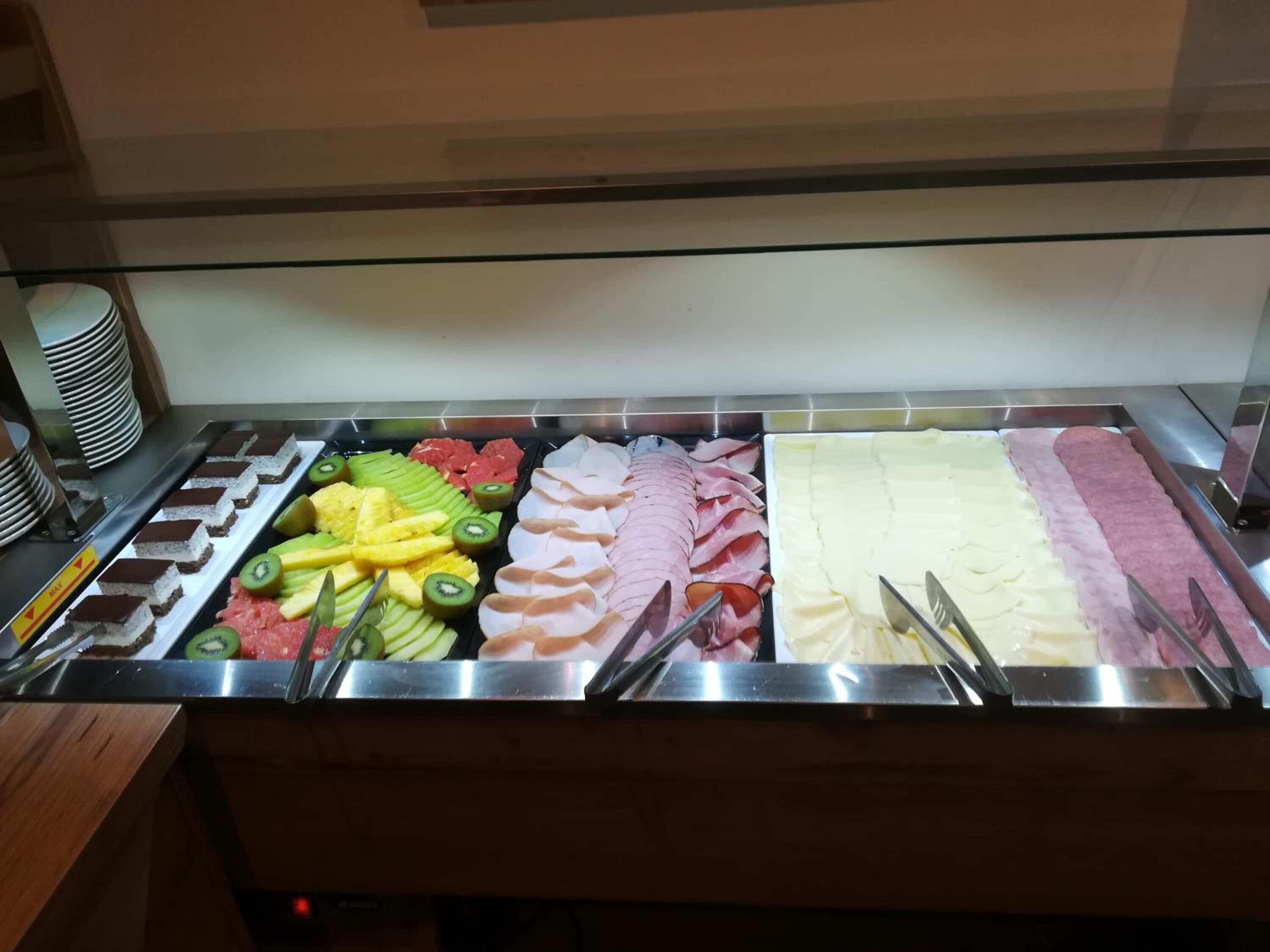 Ein reichhaltiges Buffet mit verschiedenen Speisen, darunter Obst, Fleisch und Desserts.