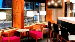 A cozy restaurant with wooden furniture, a large window with a view, and a flat-screen TV. - smartHOTEL (Dorfgastein)