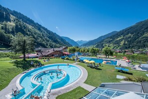 A swimming pool surrounded by a lush green landscape and mountains. - smartHOTEL (Dorfgastein)