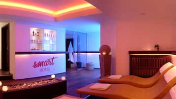 A hotel lobby with a reception desk, lounge chairs, and a bar area.