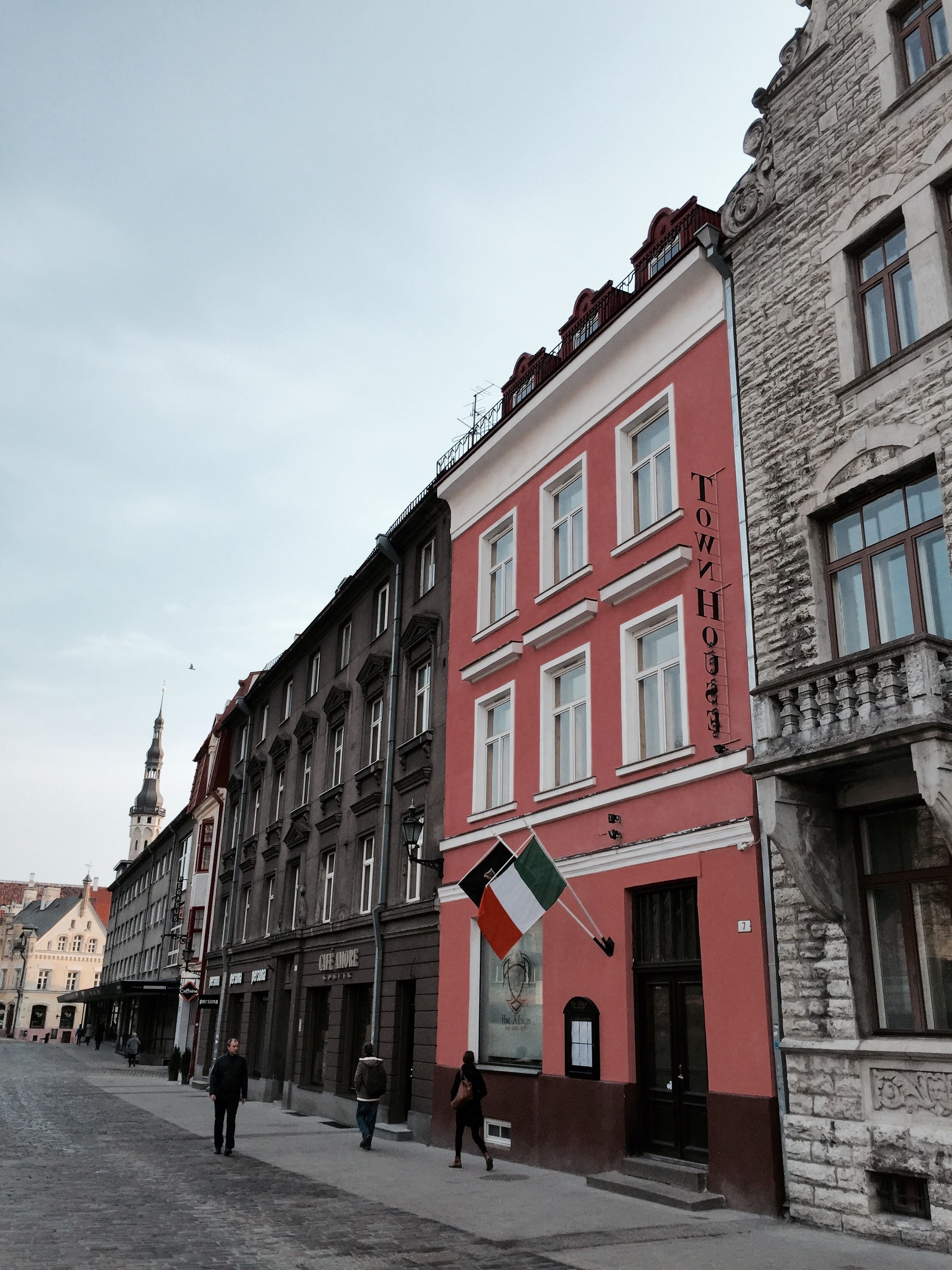 A street view with a row of buildings, including a red building with a sign that reads "TOWNHOUSE."