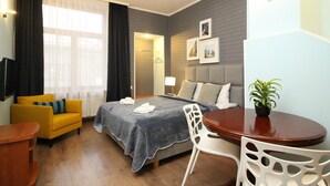 Een hotelkamer met een bed, een slaapbank, een eettafel en een stoel.