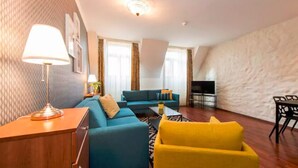 Een moderne woonkamer met een bank, een gele fauteuil, een lamp en een televisie.