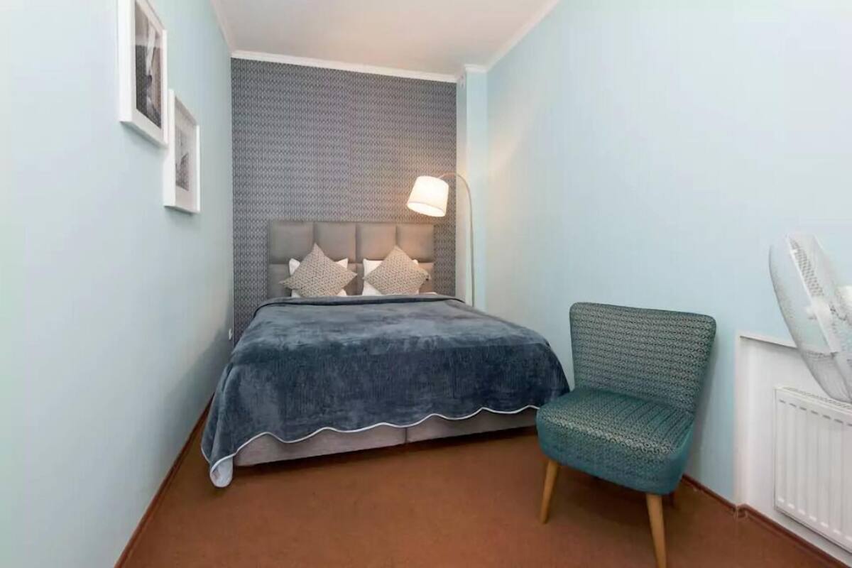 A bedroom with a bed, a chair, a lamp, and a radiator.