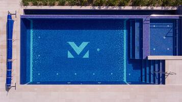 A swimming pool with a large 'V' logo, a small pool area, and a metal handrail.