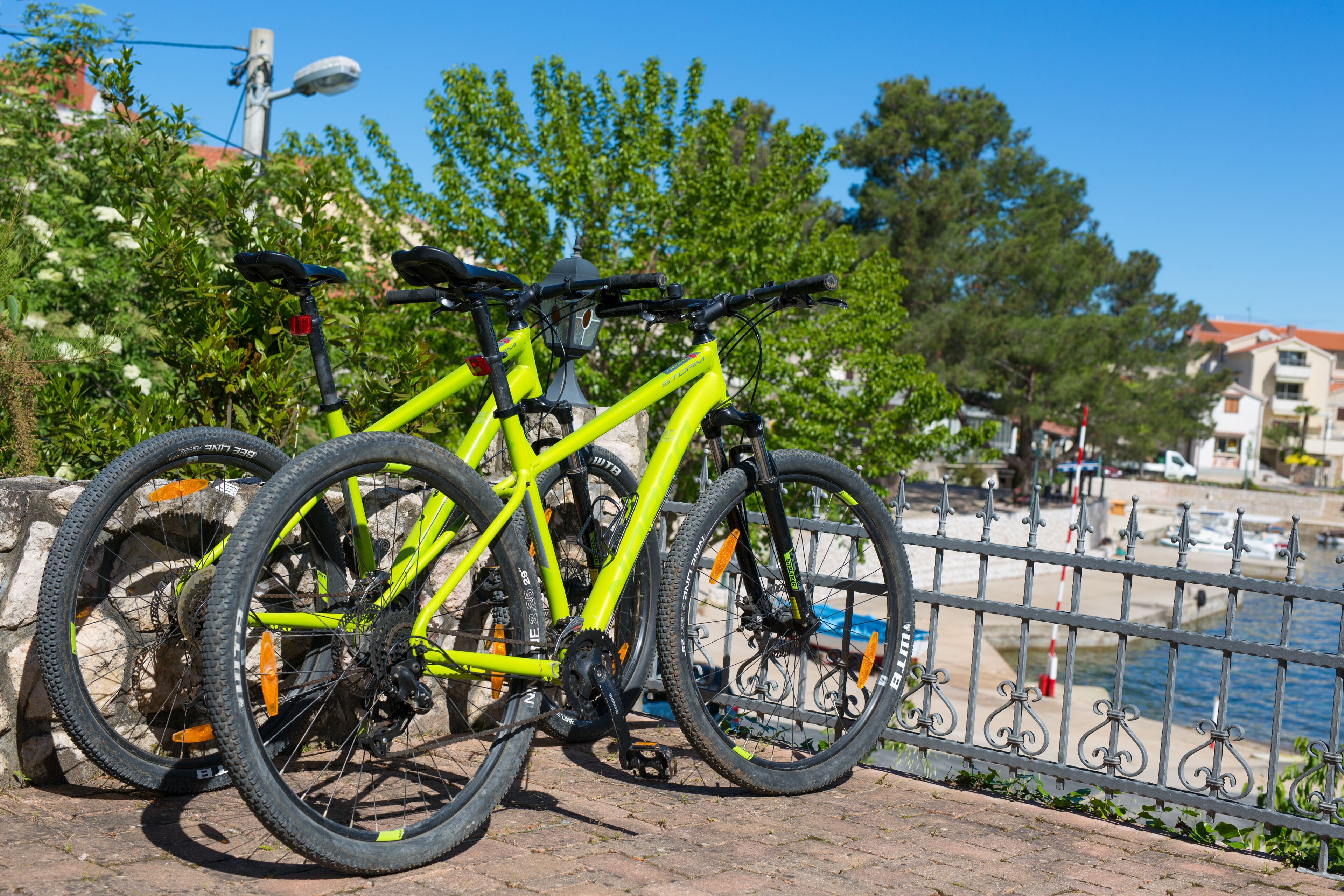Una bicicleta amarilla estacionada cerca de una valla metálica junto al paseo marítimo.