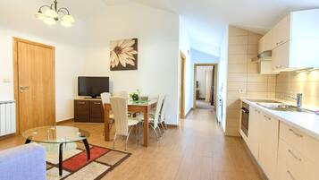 A modern apartment with a dining area, kitchen, and living space.