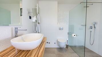 Ein modernes Badezimmer mit einem großen weißen Waschbecken, einer Duschkabine aus Glas und einem Holzkosmetikschrank.