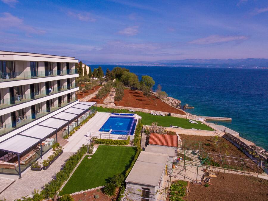 Un hotel moderno con piscina, zona de estar al aire libre y vistas al mar.